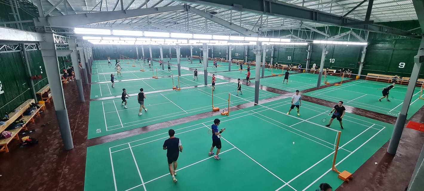 Một sân cầu lông sạch sẽ, rộng rãi với thảm xanh và vạch kẻ trắng rõ nét