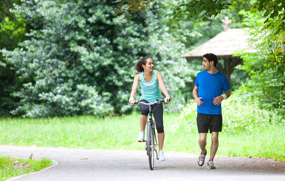 Người phụ nữ đạp xe trong công viên, hình ảnh minh họa lợi ích của đạp xe đối với sức khỏe khớp và giảm cân.