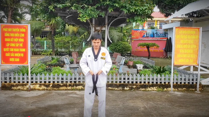 Đặt điểm giữa đai Taekwondo vào lưng, kéo đều hai đầu về phía trước