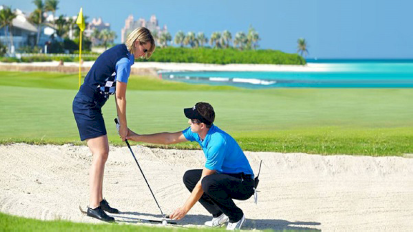 Huấn luyện viên hướng dẫn kỹ thuật đánh golf cho học viên