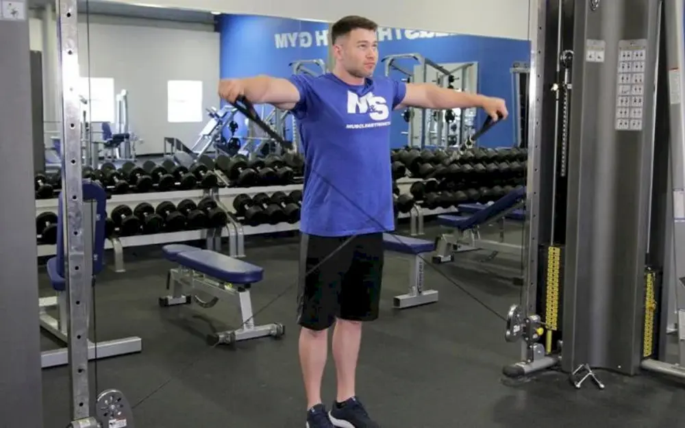 Nam vận động viên thực hiện bài tập vai Cable Lateral Raise, kéo dây cáp sang ngang để phát triển cơ vai giữa, tạo độ tròn và rộng cho bờ vai.
