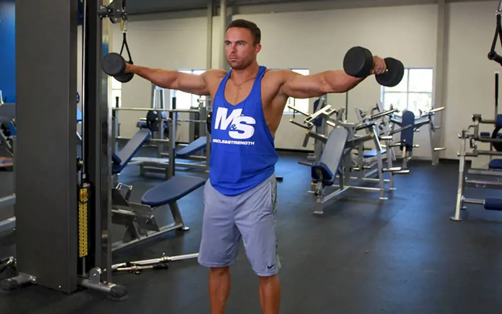 Vận động viên thực hiện bài tập vai Dumbbell 6 Ways (Raise), một chuỗi động tác phức hợp với tạ đơn để kích hoạt toàn bộ nhóm cơ vai.