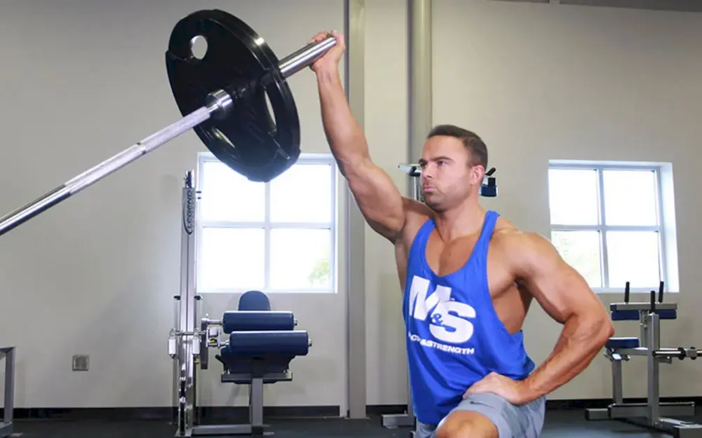 Người tập thực hiện bài tập vai Half Kneeling Landmine Press, đẩy tạ đòn từ tư thế quỳ để cải thiện sức mạnh vai và ổn định cơ core.