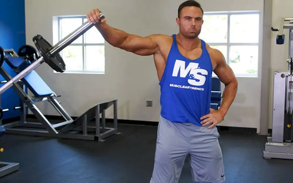 Người tập thực hiện bài tập vai Landmine Lateral Raise, nâng đòn tạ cắm vào ống landmine sang ngang để tác động vào cơ vai giữa và vai sau.