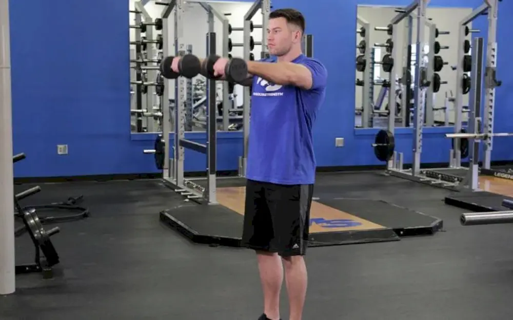 Người tập thực hiện bài tập vai Standing Dumbbell Front Raise, nâng tạ đơn thẳng ra phía trước lên ngang vai để phát triển cơ vai trước.