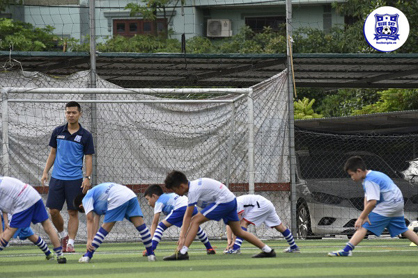 Các em học sinh tại lớp học bóng đá Blue Sky thực hiện bài khởi động và rèn luyện thể chất trước buổi tập, chuẩn bị sẵn sàng cho kỹ năng bóng đá