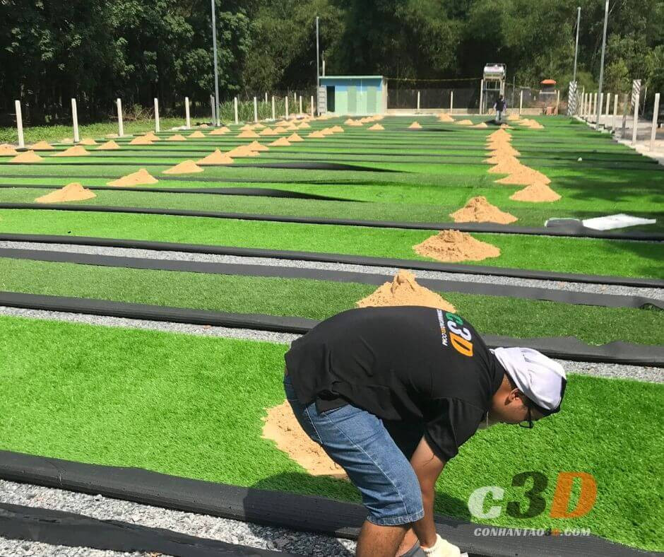 Cảnh quan thi công và hoàn thiện một dự án sân bóng đá 5 người sử dụng cỏ nhân tạo chất lượng cao, thể hiện mặt sân bằng phẳng và hệ thống chiếu sáng