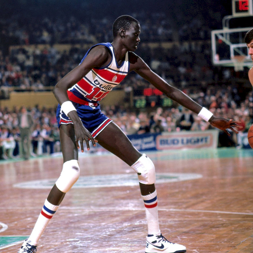 Manute Bol trên sân đấu trong trang phục màu xanh lá cây