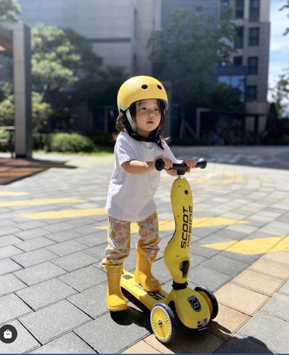 Một bé trai và một bé gái đang cưỡi xe scooter vui vẻ trên con đường lát gạch