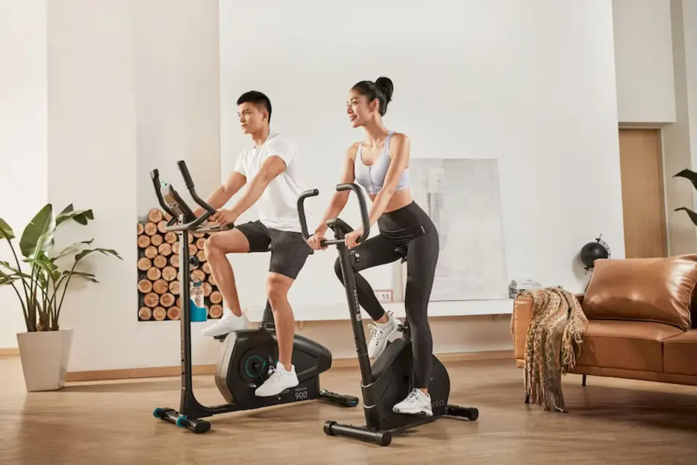 Người phụ nữ đạp xe trong phòng tập thể dục, thể hiện sự nỗ lực tập luyện giảm cân.