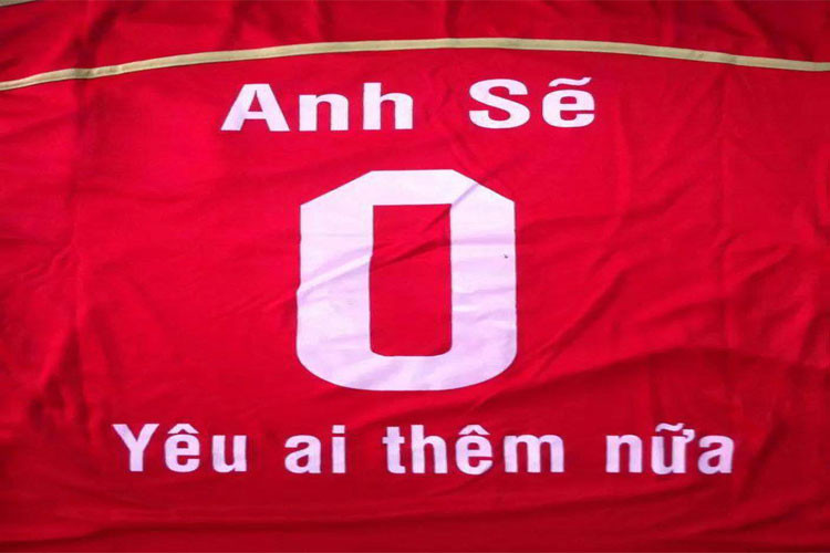 Hình ảnh một đội bóng đang đứng trên sân, một cầu thủ có tên áo &quot;Anh 0 yêu ai thêm nữa&quot;, thể hiện sự sáng tạo và phong cách riêng