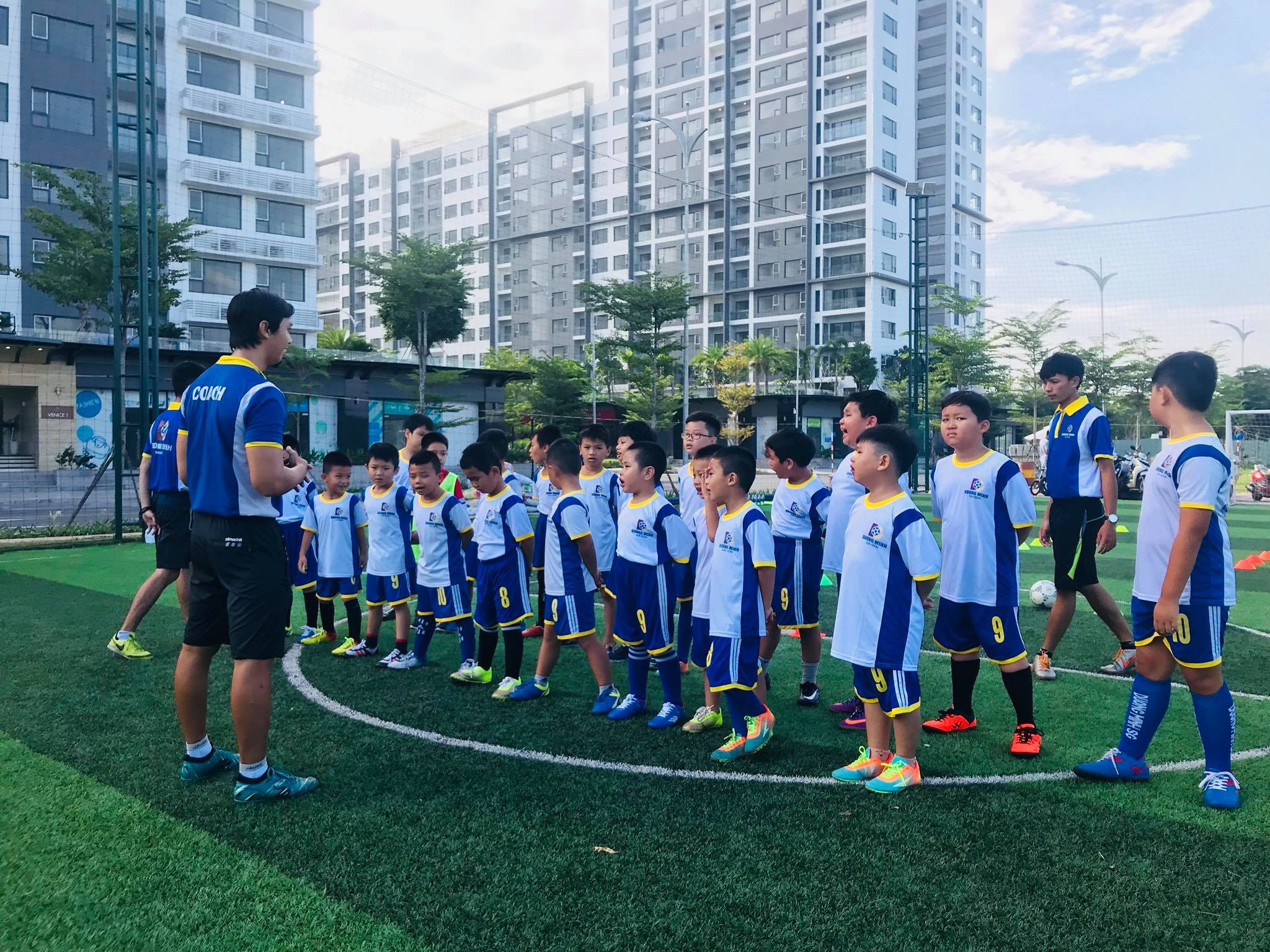 Huấn luyện viên đang hướng dẫn các cầu thủ nhí tập luyện kỹ thuật trong buổi tập tại sân bóng đá TPHCM, thể hiện hoạt động clb bóng đá tphcm tuyển dụng