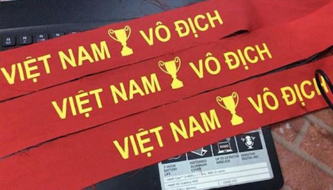 Mô tả hình ảnh các cổ động viên hô vang khẩu hiệu cổ vũ bóng đá trên khán đài, thể hiện sự nhiệt huyết và tinh thần đoàn kết