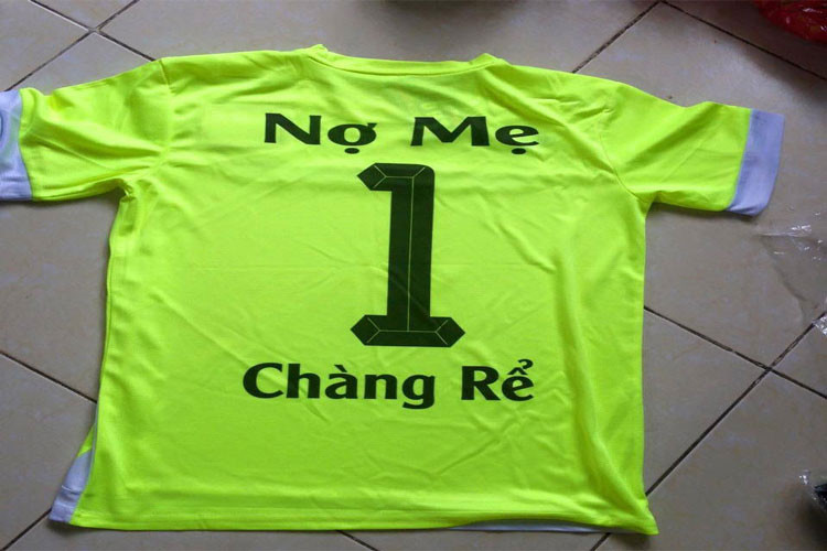 Một nhóm cầu thủ bóng đá đang đứng trên sân, một số người mặc áo có tên hài hước liên quan đến tình trạng FA, thể hiện tinh thần vui vẻ của đội bóng