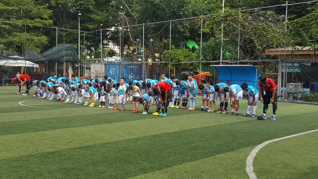 Một nhóm học viên và huấn luyện viên VJSS chụp ảnh lưu niệm tại sân bóng, thể hiện sự gắn kết và tinh thần thể thao của trung tâm bóng đá nam việt