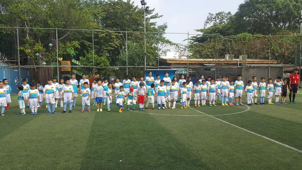 Sân bóng đá với các cầu thủ nhí đang tập luyện dưới sự hướng dẫn của huấn luyện viên